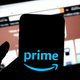 A phone with the Amazon Prime logo is shown with Amazon.com's storefront in the background.
